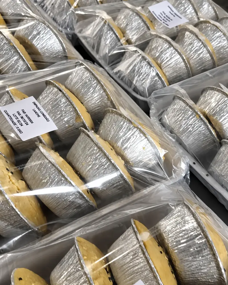 Massas de bolo embaladas em filme e identificadas, empilhadas no estoque da Rôof